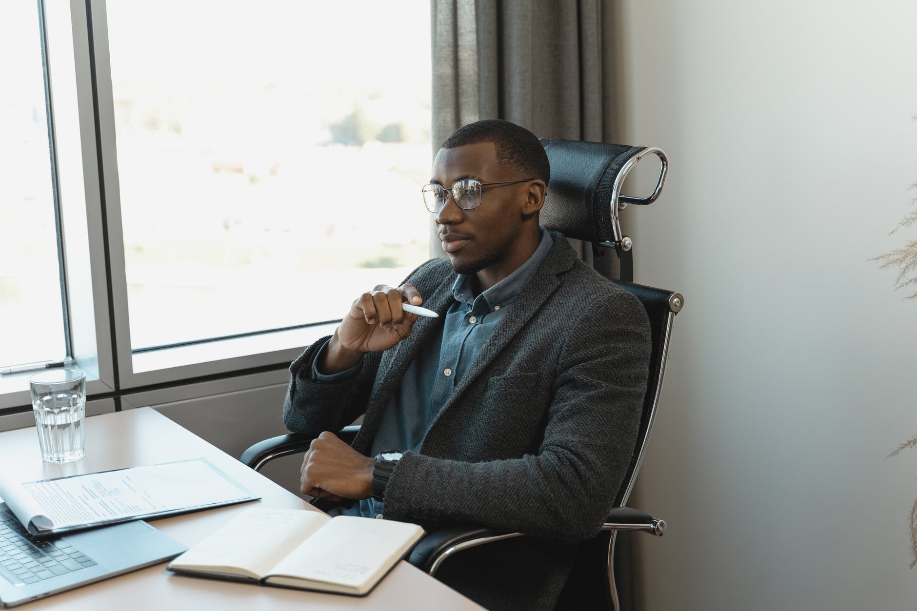 man in gray blazer writing down on paper