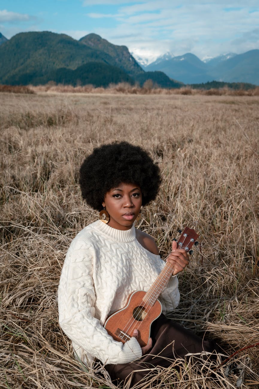 woman in white sweater holding a string instrument
